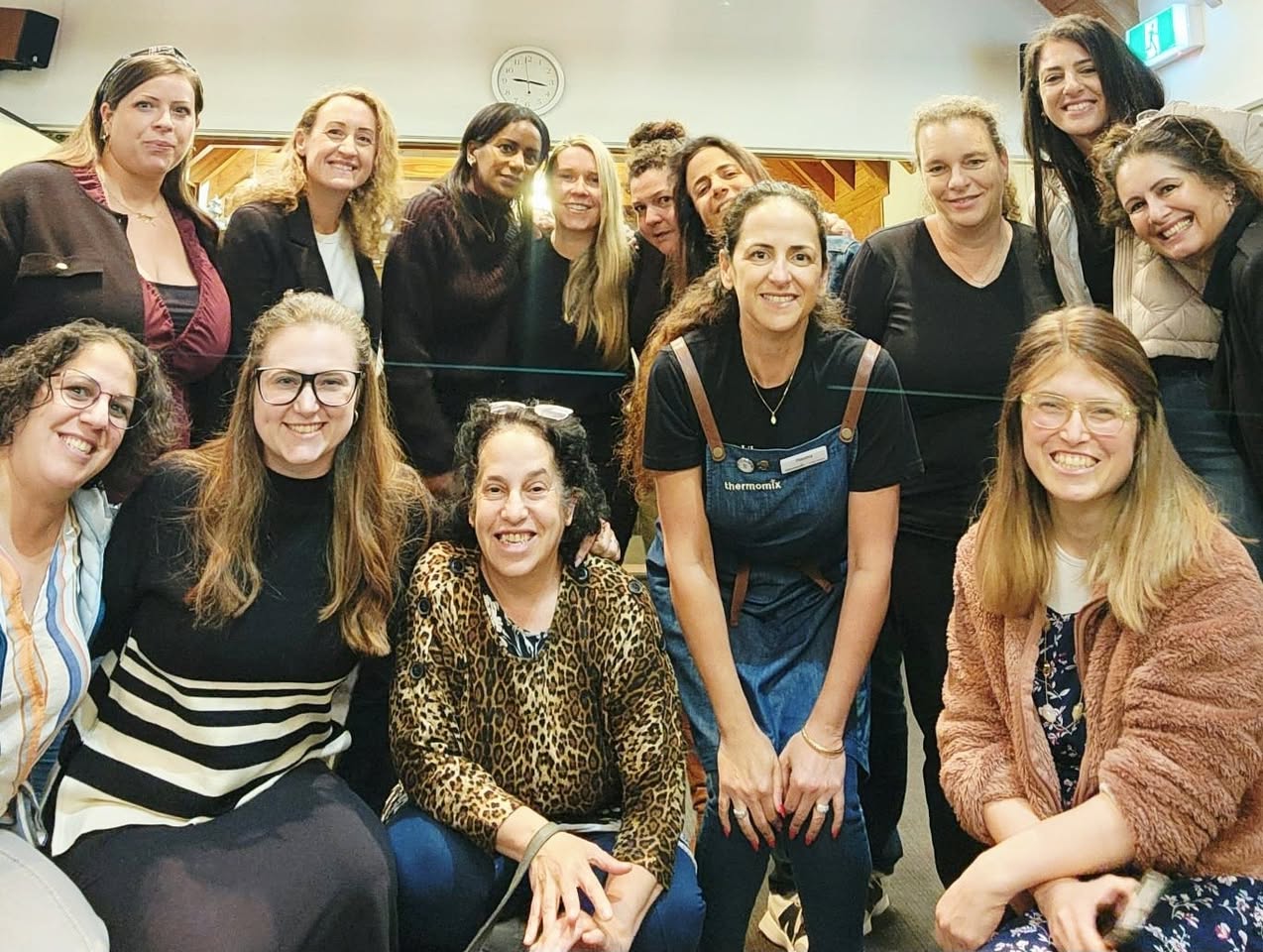 A large group of smiling women gathered together indoors at 788