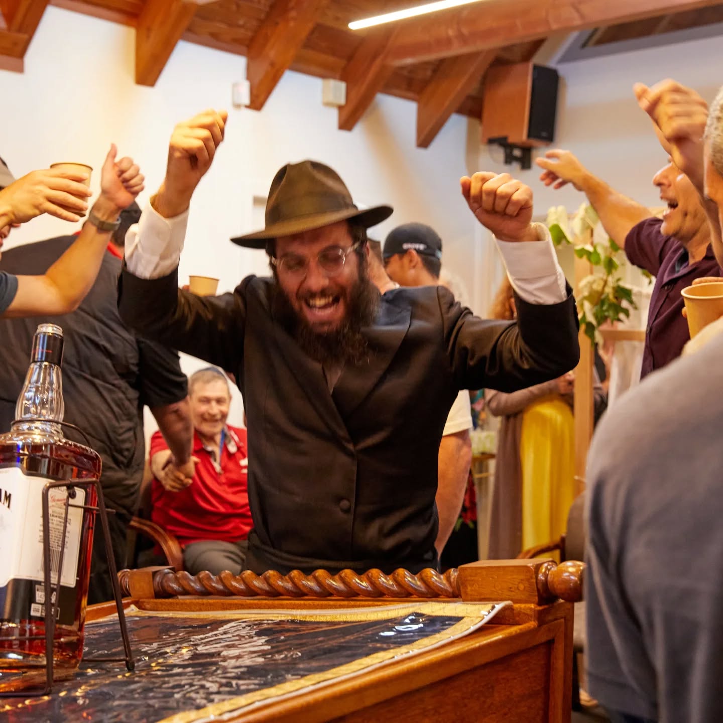 A rabbi dancing with arms raised, surrounded by celebrating community members