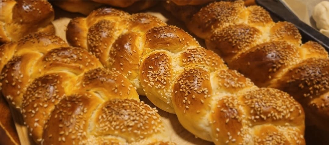 A tray of freshly baked sesame-topped challah loaves