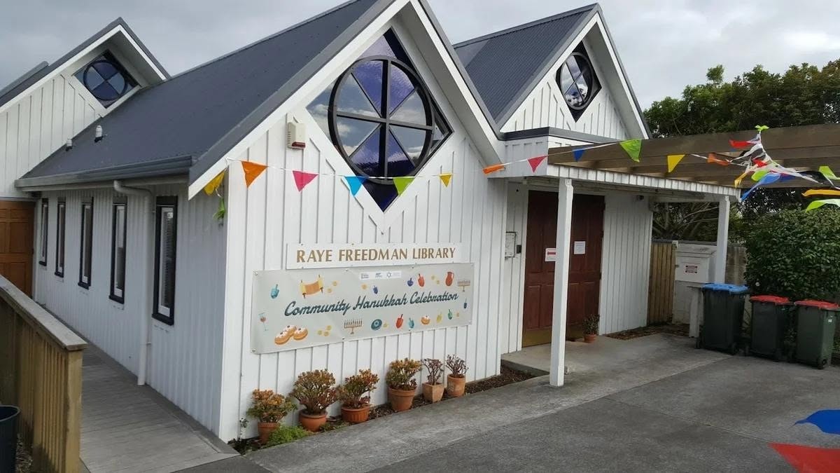 The white weatherboard front of the Raye Freedman Library at 788 Remuera Road, decorated with colourful Chanukah bunting